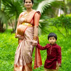 The sweet anticipation of a new arrival is a precious family moment. We specialize in maternity shoots that include older siblings, capturing the unique bond and excitement as your family grows. This outdoor portrait in a beautiful silk saree shows a quiet, loving moment between a mother and her son.