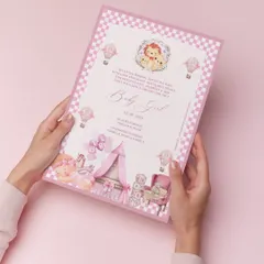 A heartwarming birth announcement for a baby girl. This printed card is filled with pastel charm, from the pink checkered border to the delicate illustrations of a nursery, celebrating a beautiful new beginning.
