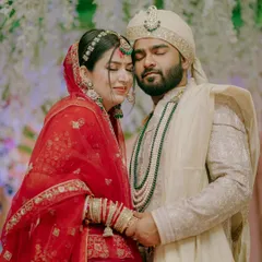 An intimate portrait of a North Indian couple, holding each other close. The rich red of the bride's lehenga and the groom's elegant sherwani create a timeless image of love and commitment.
