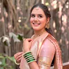 A candid, happy moment captured. Her radiant smile complements the soft pink makeup, traditional green bangles, and gold jewelry, showcasing the complete, joyful look of a Maharashtrian bride.