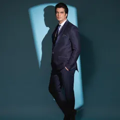 A side profile shot from the same commercial shoot, highlighting the clean lines and perfect fit of the tailored suit.