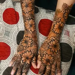 An intricate floral henna design with large, beautiful flowers covering the hands.