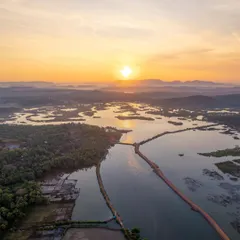A hidden spot in Kumta where the Aghanashini river snakes through the landscape at sunrise. This aerial view showcases the salt pans and marine activities of the local villages, a perspective you can only get from the sky.