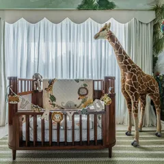 The centerpiece of this nursery is a beautiful wooden crib, complemented by a life-sized giraffe. The jungle mural and scalloped curtains create a soft, dreamy atmosphere perfect for a baby.