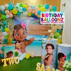 An adventurous Moana theme, perfect for a tropical birthday celebration. This decor features a large Baby Moana cutout, a beach scene backdrop, and pedestals customized with photos of the birthday girl dressed as Moana.