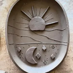 A close-up of the sun and moon trinket dish before glazing. I sculpted each element by hand to create a celestial design.