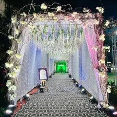This magical Sangeet entrance features a rustic branch archway and a tunnel of hanging white wisteria and fairy lights, creating a path that feels like walking through an enchanted forest.