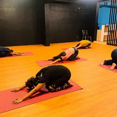 The class in a child's pose during a cool-down sequence. This stretch is essential for releasing tension in the back and shoulders after a tough workout.