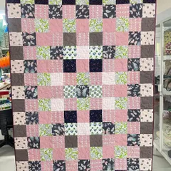 This memory quilt was made for a client from her daughter's frocks and T-shirts. The pink, green, and butterfly-print fabrics are arranged in a cheerful checkerboard pattern.