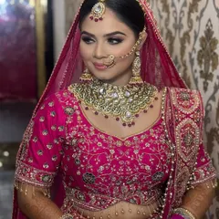 A beautiful candid-style shot. The bride looks off to the side, showcasing her flawless profile and the way the dupatta frames her face and hairstyle.
