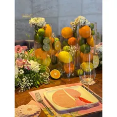 This summer birthday tablescape is bursting with freshness, using tall glass vases filled with whole lemons, limes, and oranges, interspersed with delicate floral bouquets.
