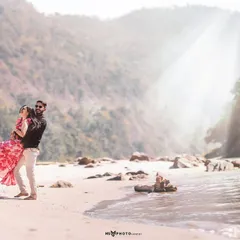 A playful lift on the beach by the river, with the morning sun creating a beautiful flare. This captures a moment of pure joy and fun between the couple.