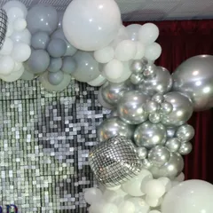 A glamorous silver and white balloon garland with a disco ball, part of a festive anniversary party setup.