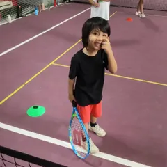 A happy player from our Red Batch, racket in hand and ready to learn. We focus on positive reinforcement to build a lifelong love for the game.