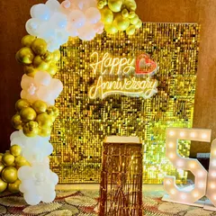 Celebrating a golden 50th anniversary in style. This glamorous photo corner includes a shimmering gold sequin backdrop, large light-up marquee numbers, and an elegant organic balloon arch in white and gold.