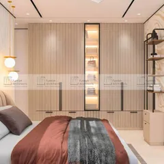 A modern bedroom design featuring a floor-to-ceiling wardrobe with fluted paneling. A central glass-paneled section with internal lighting turns the wardrobe into a beautiful display for bags and accessories.