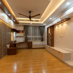 This spacious room combines a living area with a dedicated study nook. The design features a mix of wood tones and white finishes, complemented by layered ceiling lights, creating a multi-functional and cohesive living space.