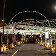 A magical night-time entrance created with a series of illuminated arches and a pathway lined with glowing lanterns and candles. This design creates a warm and inviting journey into the heart of the celebration.