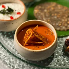 A close-up of one of the flavourful curries from our Navratri Thali, garnished with crispy lotus stem chips.