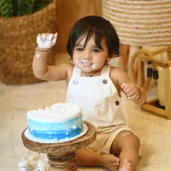 A playful shot from a first birthday cake smash, with the baby boy showing off his frosting-covered hands.