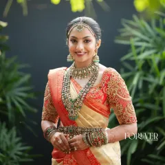 A quintessential South Indian bridal look that feels both classic and fresh. This bride is radiant in a timeless red and cream Kanjivaram saree, which I paired with a heavily embroidered blouse featuring a delicate net back for a touch of modern grace.