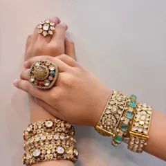 Bangles that blend tradition with trend. This image showcases various styles, from emerald-studded kadas to classic polki bangles, paired with statement rings.