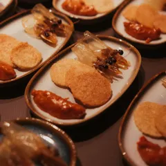 An inventive seafood appetizer. This dish features crispy fried prawn heads for texture, served alongside prawn crackers and a dollop of our house-made sambal for a spicy kick.