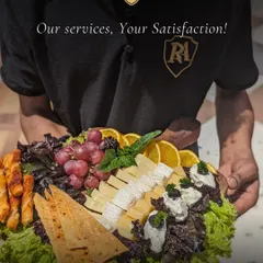 My commitment is to your satisfaction, delivered on a platter. A member of my professional staff presents a beautifully arranged cheese and fruit platter, showcasing the quality of ingredients and attention to detail I bring to every event.