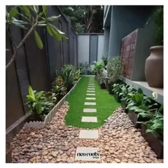 This narrow side yard was transformed into a contemporary Zen garden. A central path of stone pavers on a bed of artificial grass is flanked by river stones and minimalist plantings, creating a clean, orderly, and tranquil passage.
