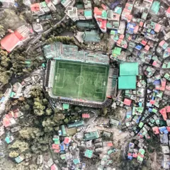 A top-down view of a football stadium in Gangtok, Sikkim, surrounded by a dense, colorful cityscape. This shot highlights the challenge of urban planning in a hilly region.