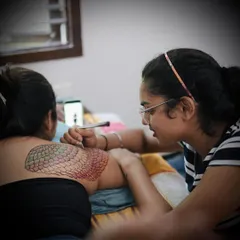 A behind the scenes shot of me applying a colorful mermaid scale pattern on the model's back. This shows the versatility of colored henna for creating imaginative and large scale body art.
