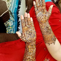 A beautiful example of asymmetrical bridal mehendi, where each hand tells its own story. One hand features bold, open florals, while the other has a more detailed, traditional pattern.