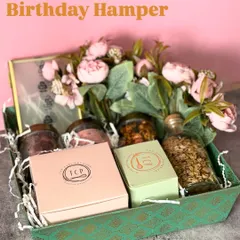 This birthday hamper in a rustic green tray is bursting with color and flavor. It's packed with granola, assorted nuts, and our signature cookie boxes, all adorned with a beautiful floral arrangement.