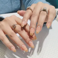 A festive and elegant design featuring a nude base with a cascading gold glitter ombré from the tips, accented with tiny pearl details.