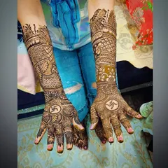 A top-down view of the swastika mehandi, showing the full design extending up the arms with traditional patterns.