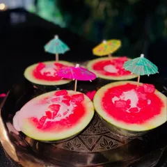 A creative presentation of watermelon ice cream, served in hollowed-out watermelon shells and topped with cocktail umbrellas.