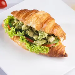 The Pesto Chicken Croissant Sandwich. Tender chicken tossed in aromatic pesto, layered with fresh vegetables inside our signature croissant for a flavourful and satisfying meal.
