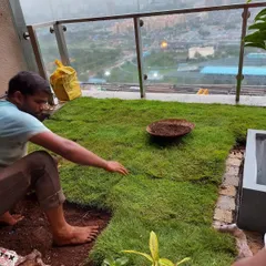 My team member is carefully laying down sections of natural lawn on a terrace, piecing them together to create a seamless green carpet.