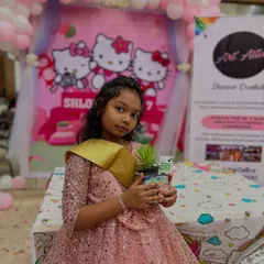 The birthday girl proudly holding the sand art terrarium she made. It's so rewarding to see kids enjoying the creative process on their special day.