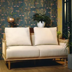 Our signature two-seater sofa combines a solid Teak wood frame with delicate, handwoven cane panels. This piece exemplifies our commitment to blending traditional craftsmanship with clean, modern lines for a timeless aesthetic.