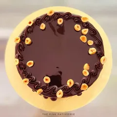A top-down view of the hazelnut crunch cake, showing the glossy chocolate glaze and scattered hazelnuts.