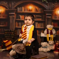 A toddler sits proudly with a wand and broomstick in our magical library. We provide a variety of props to create a complete narrative for our themed photoshoots.