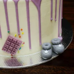 A close-up of the tiny fondant baby booties on the purple drip cake. It's these small, handcrafted details that make a cake extra special.