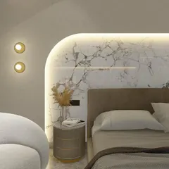 A design detail for a daughter's bedroom, featuring a custom-made curved headboard backdrop in white marble. The integrated backlighting creates a soft, ambient glow.