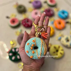 Holding one of our mint-chocolate chip inspired donut keychains. Each one is attached to a high-quality gold-colored clasp with a matching tassel for extra style.