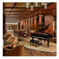 The piano lounge at the Sheraton Bangalore, designed as a sophisticated retreat for guests. The space features rich wood wall paneling, comfortable seating arrangements, and a grand piano as the centerpiece.