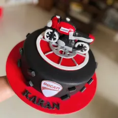 A sleek Ducati motorcycle cake for a bike enthusiast. The cake is designed to look like a wheel, topped with a detailed, edible model of the motorcycle.