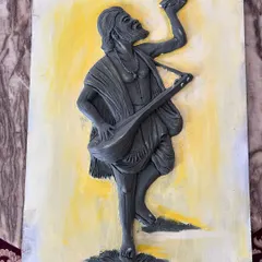 The clay sculpture of Kanaka Dasa is complete and set against a simple painted background, showing the raw texture of the artwork before final touches.