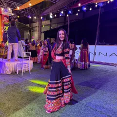 Posing in my traditional black chaniya choli at a Navratri event. The background shows the stage setup with live performers, a key element of the events I manage.