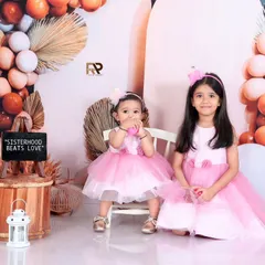 A sweet moment between two sisters, dressed in matching pink dresses. This portrait beautifully captures the special bond of sisterhood.